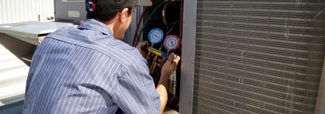 HVAC technician servicing a condenser unit in Elko New Market
